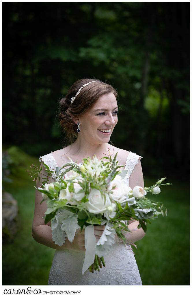 a beautiful portrait of a bride, holding a bouquet of white, pink, and green, and smiling at someone off camera