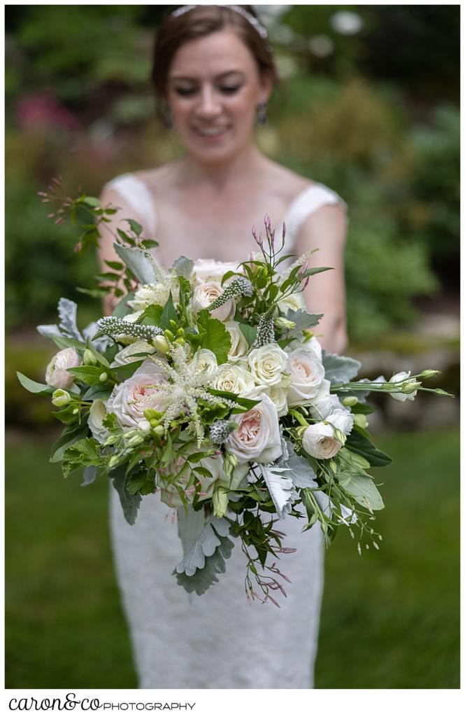 bride holding a beautiful bridal bouquet by Fleurant Designs, the flowers are pastel pink, white, cream, and green