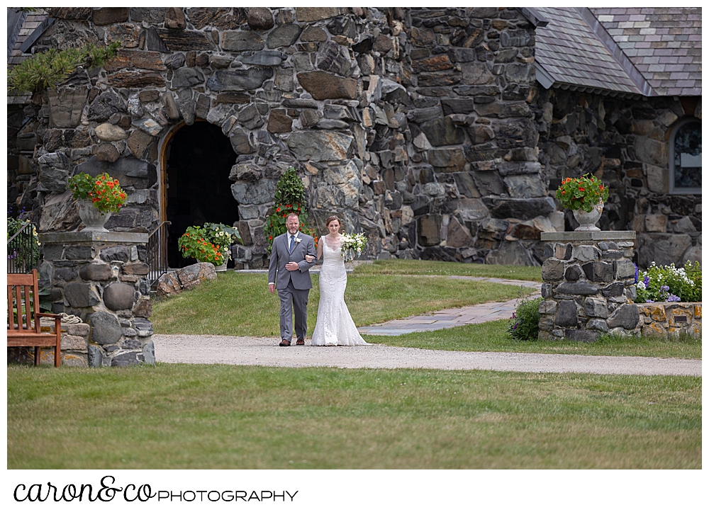 A bride and her father walk from St. Ann's by-the-sea Episcopal Church in Kennebunkport, Maine, toward the outdoor ceremony site