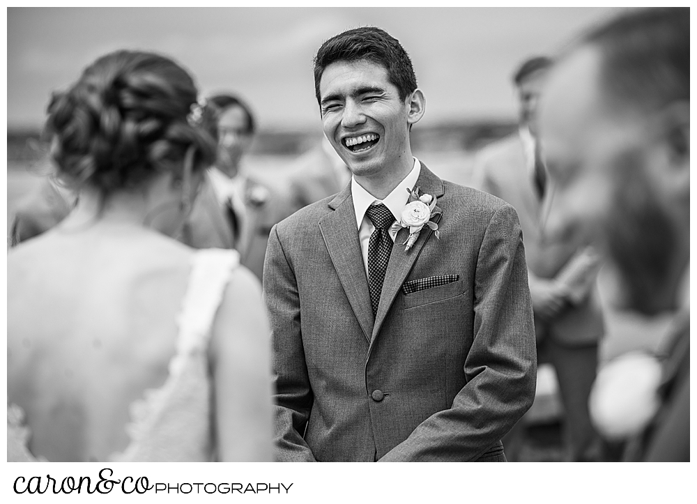 black and white photo of a groom laughing during the wedding ceremony