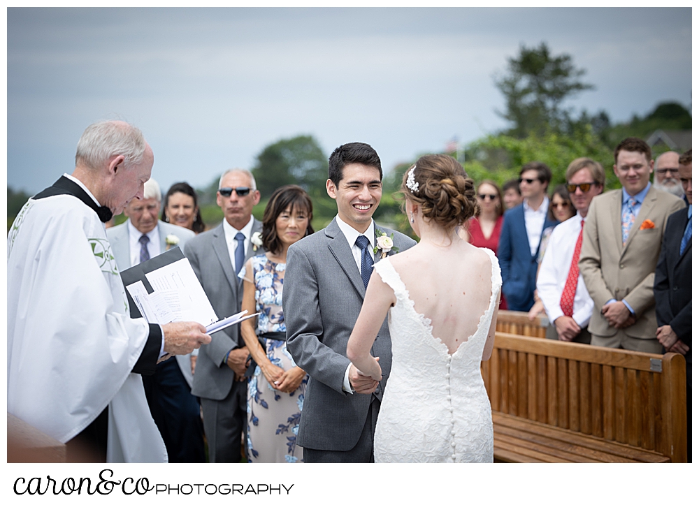 a groom smiles at his bride during a St. Ann's by-the-sea Episcopal Church, Kennebunkport, Maine