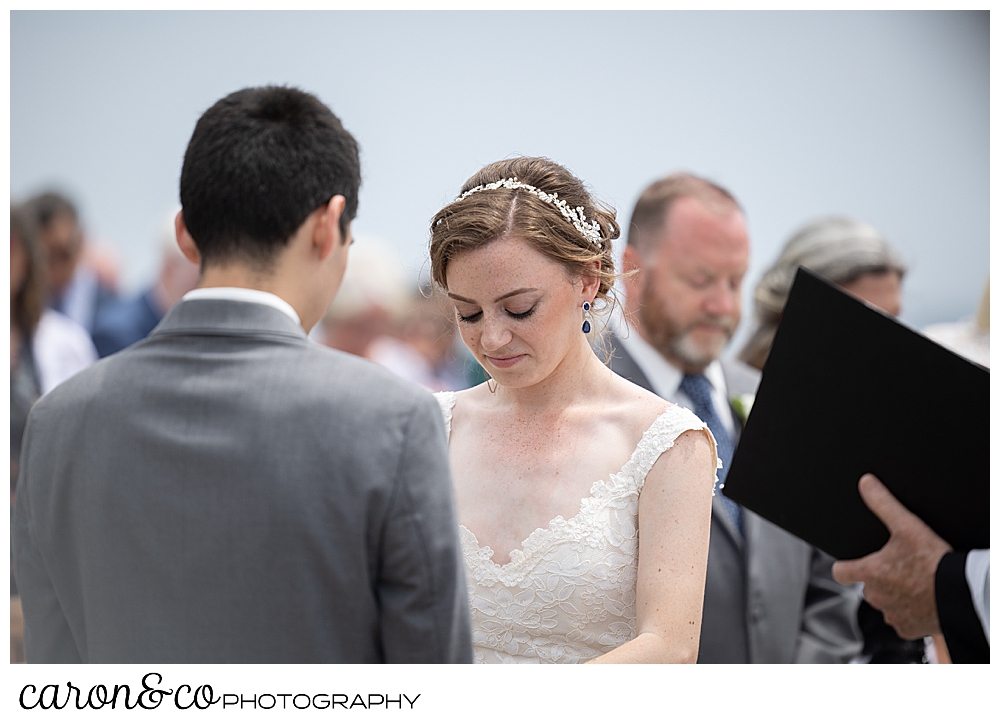 a bride bows her head during an outdoor wedding ceremony