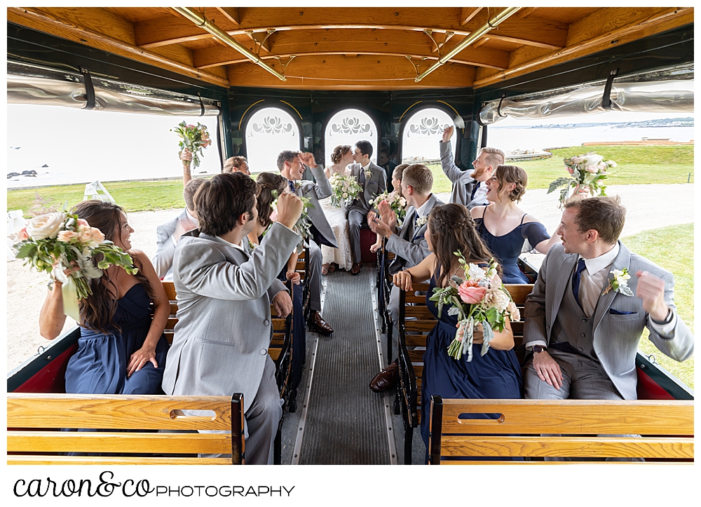 a bride and groom kiss on a trolley, while their bridal party cheers