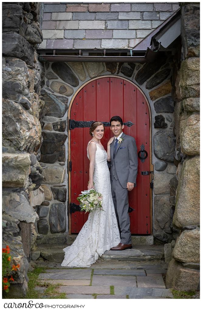 a bride and groom stand in front of a red door at St. Ann's by-the-sea Episcopal Church, Kennebunkport, Maine