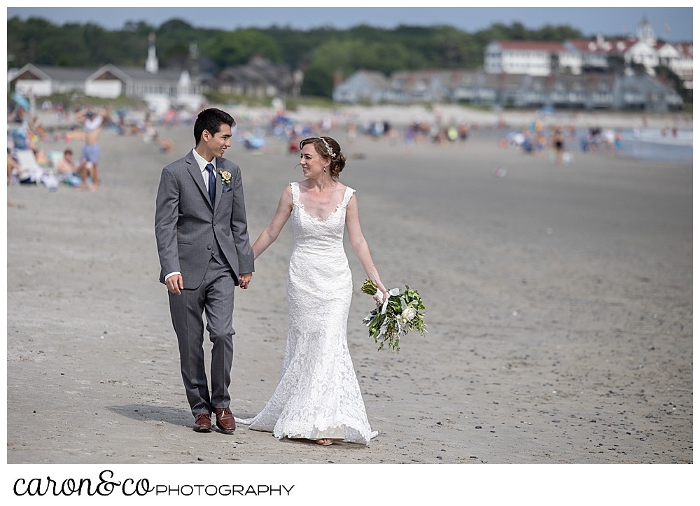 a bride and groom walk on Gooch's Beach in Kennebunk, during their Kennebunk Maine wedding