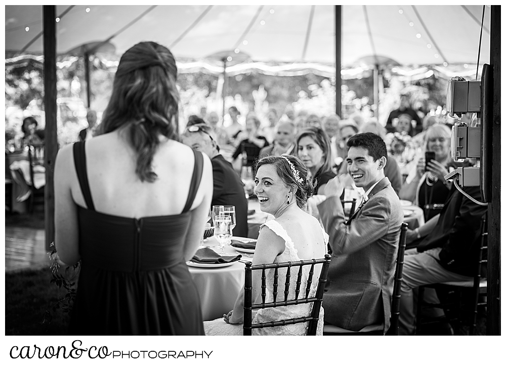 a bridesmaid with her back to the camera, proposes a toast to the bride and groom, who are looking on during their Kennebunk Maine wedding reception