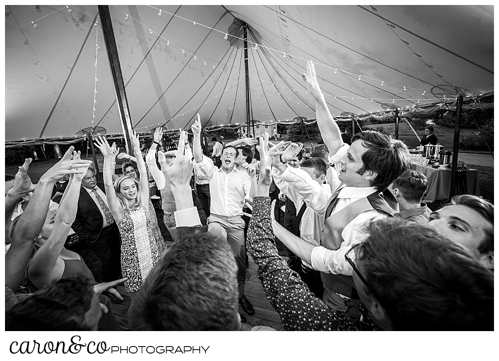 black and white photo of guests dancing with their arms raised, during a tented Kennebunk Maine wedding