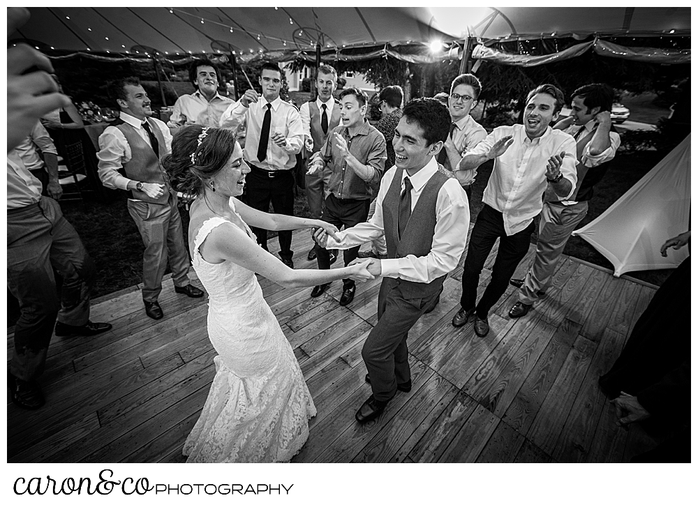 black and white photo of a bride and groom dancing, surrounded by friends at a coastal Maine tented wedding reception