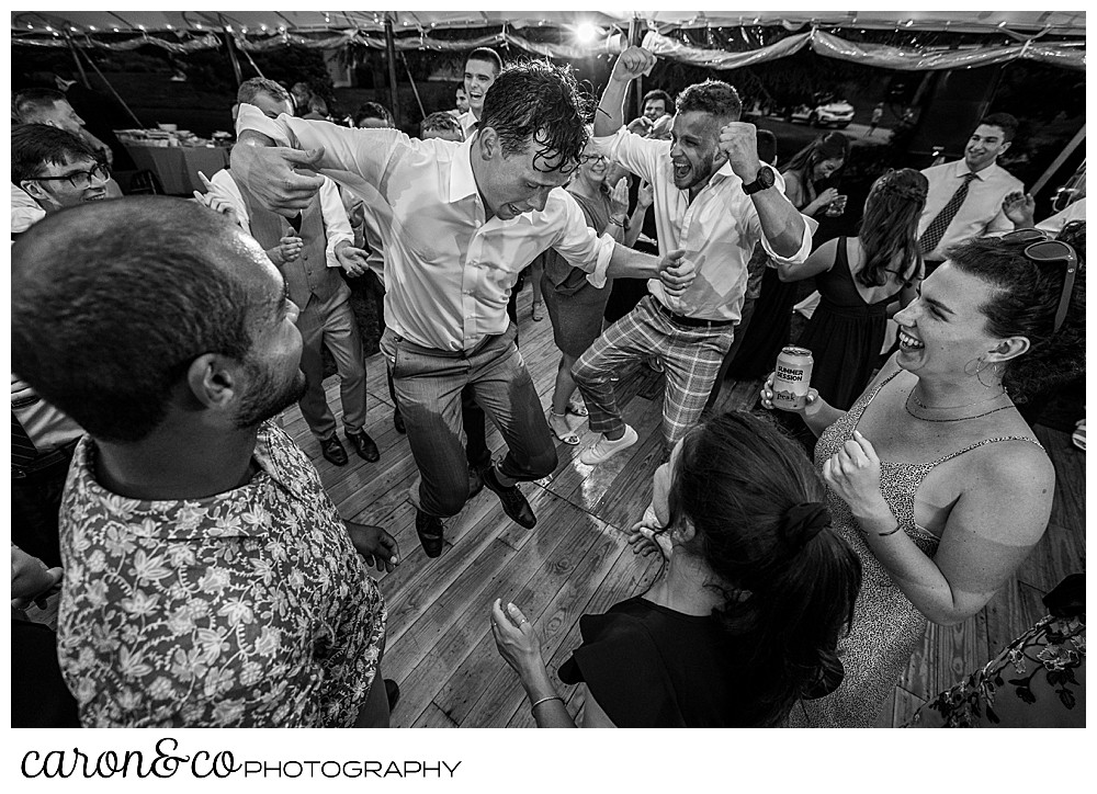 black and white photo of a bunch of men dancing during a Maine coast tented Kennebunk wedding reception
