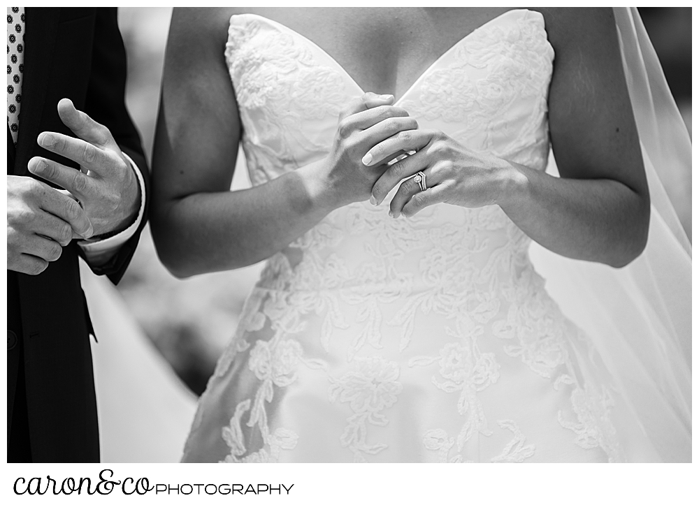 a black and white photo of a bride and groom, they are feeling the new wedding bands on their hands