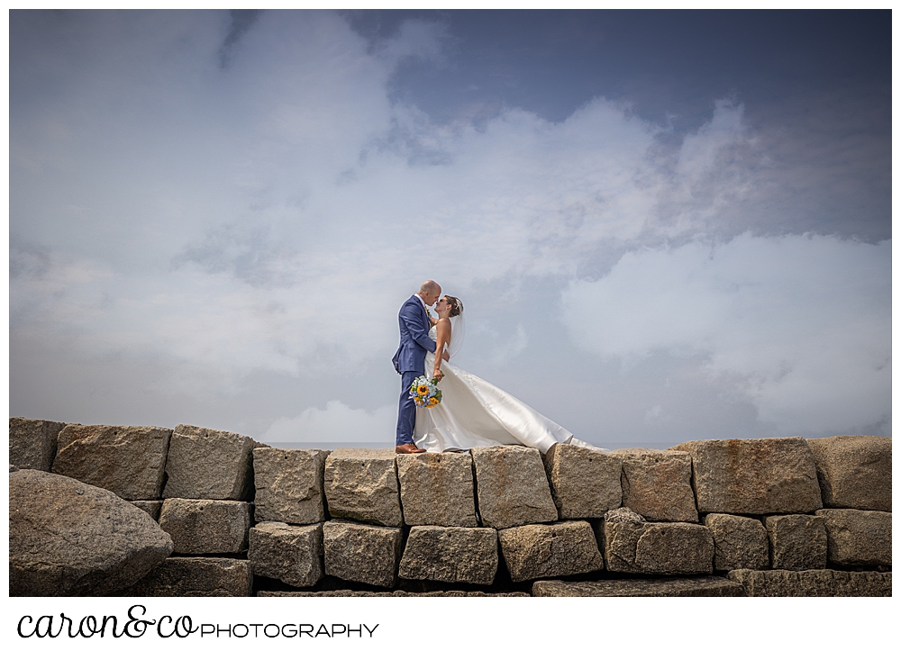 a bride and groom stand on the Kennebunkport Breakwater, they're facing one another and are about to kiss, Kennebunkport Maine