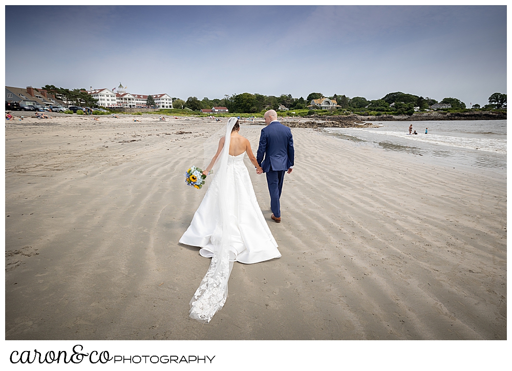 a bride and groom walk away from the camera on the Colony Beach, Kennebunkport, Maine