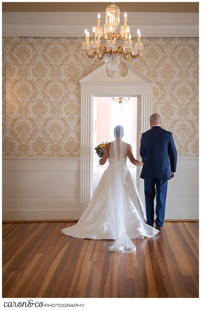 a bride and groom are walking through a banquet room at the Colony Hotel, during their Kennebunkport wedding at the Colony Hotel