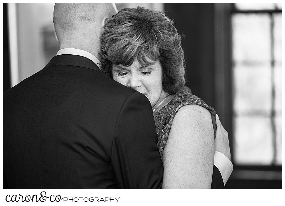 black and white photo of a mother son dance, the groom's back is to the camera, his mother's head is on his shoulder, her eyes are closed