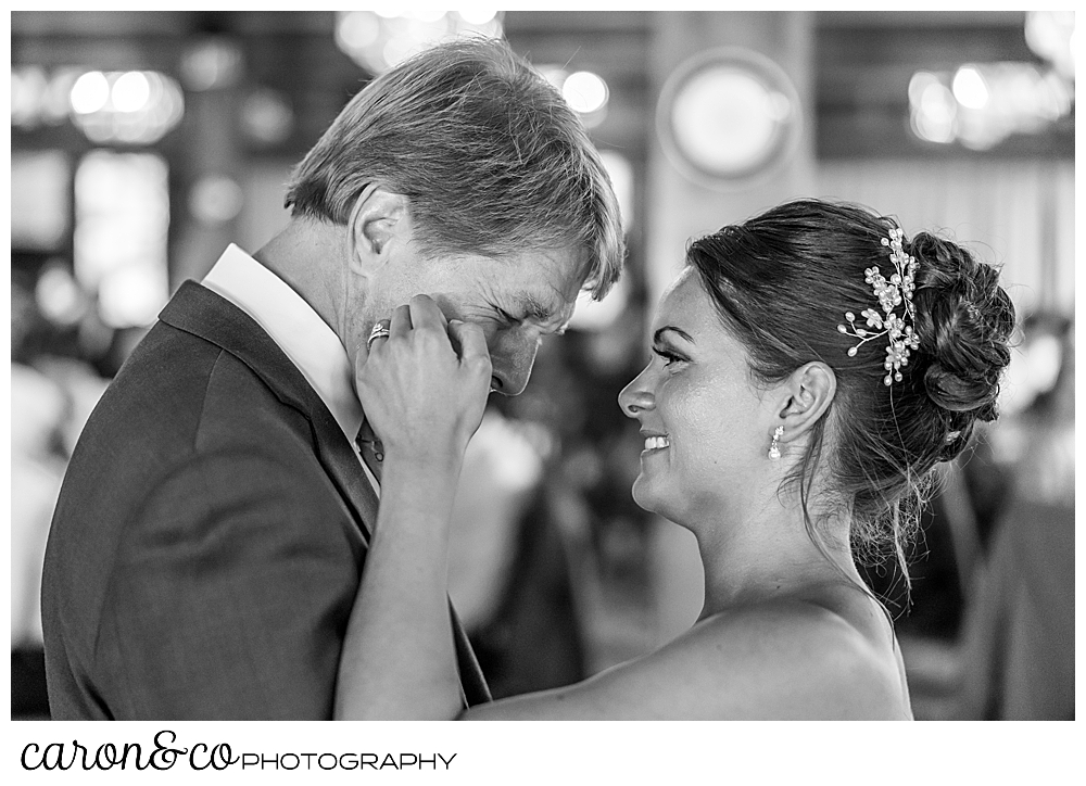 black and white photo of a bride and her father during the father daughter dance, the bride is brushing away a tear on her dad's cheek, at a Kennebunkport wedding at the Colony Hotel