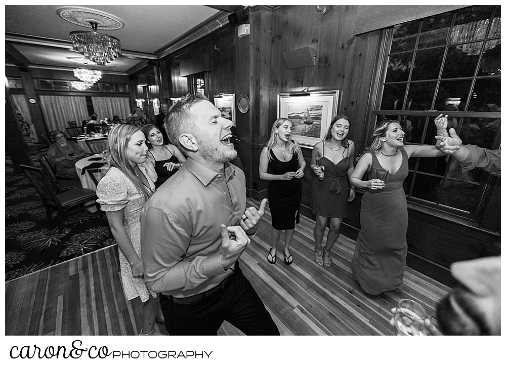 black and white photo of a ban dancing and singing, while guests dance around him