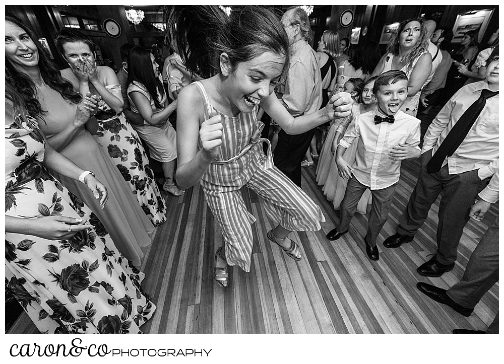 black and white photo of a woman in a striped jumpsuit, dancing while other guests dance around in the background