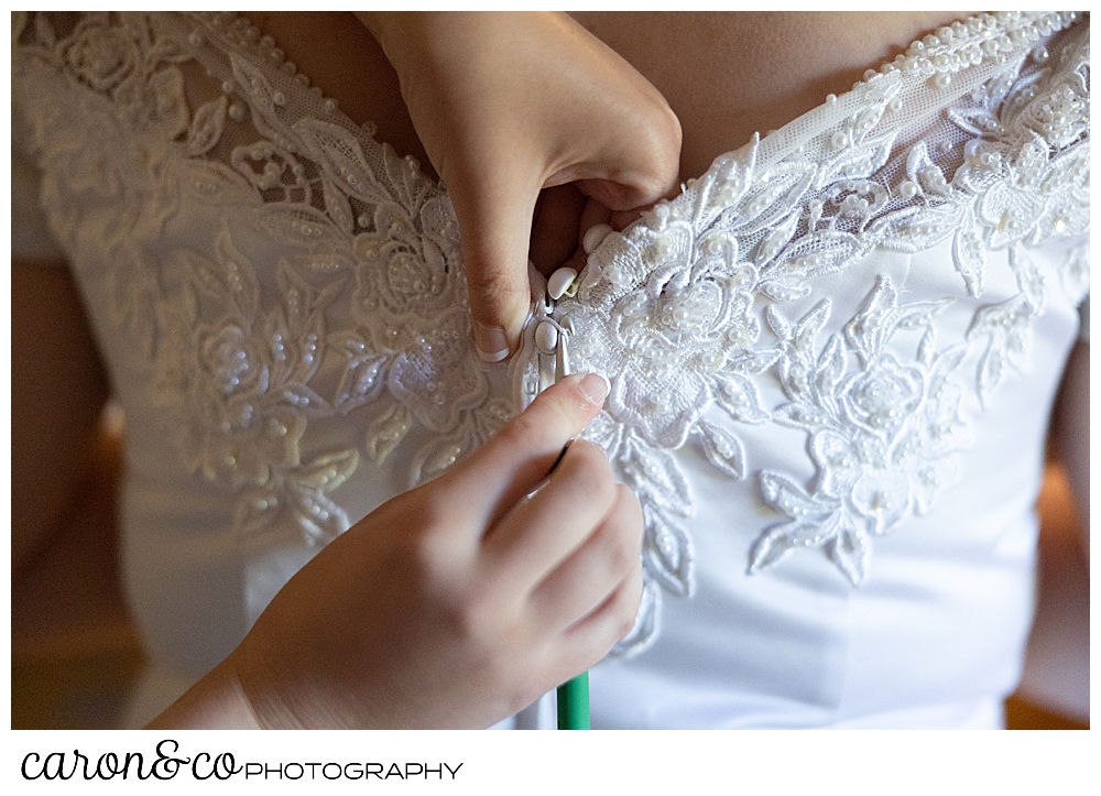 wedding dress being fastened in the back with a crochet hook