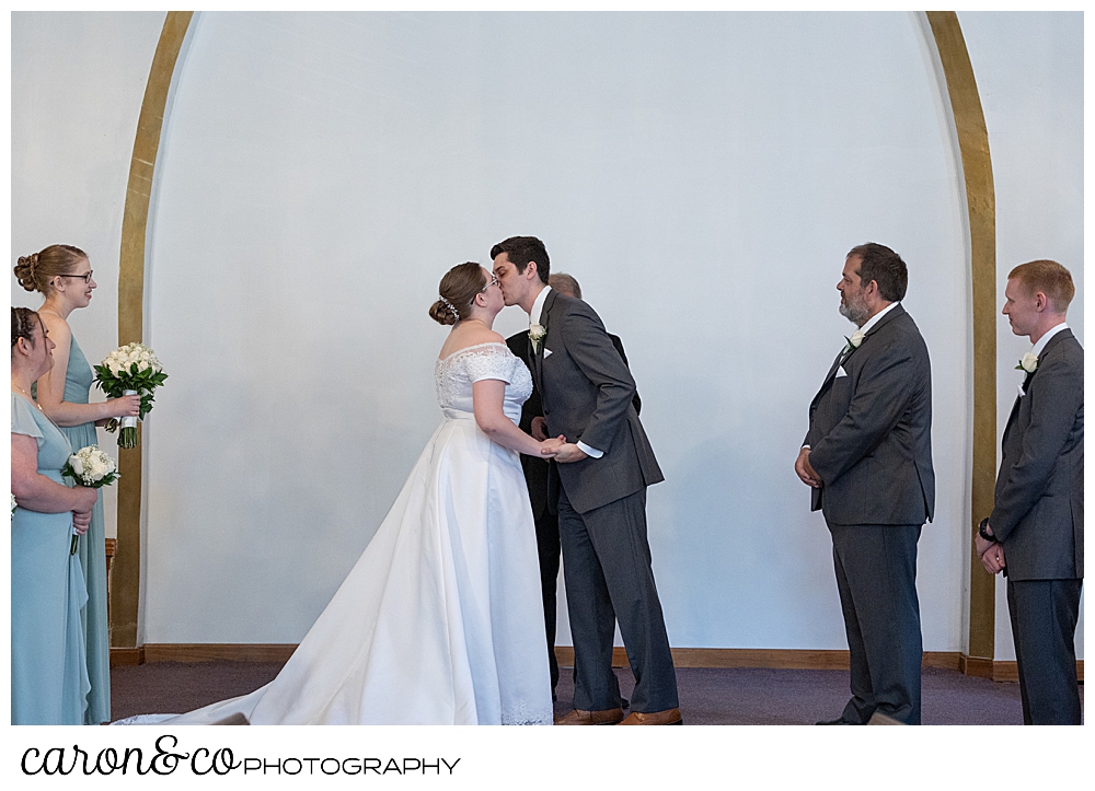 a bride and groom have their first kiss at the Peru Maine Baptist Church, during a sweet western Maine wedding