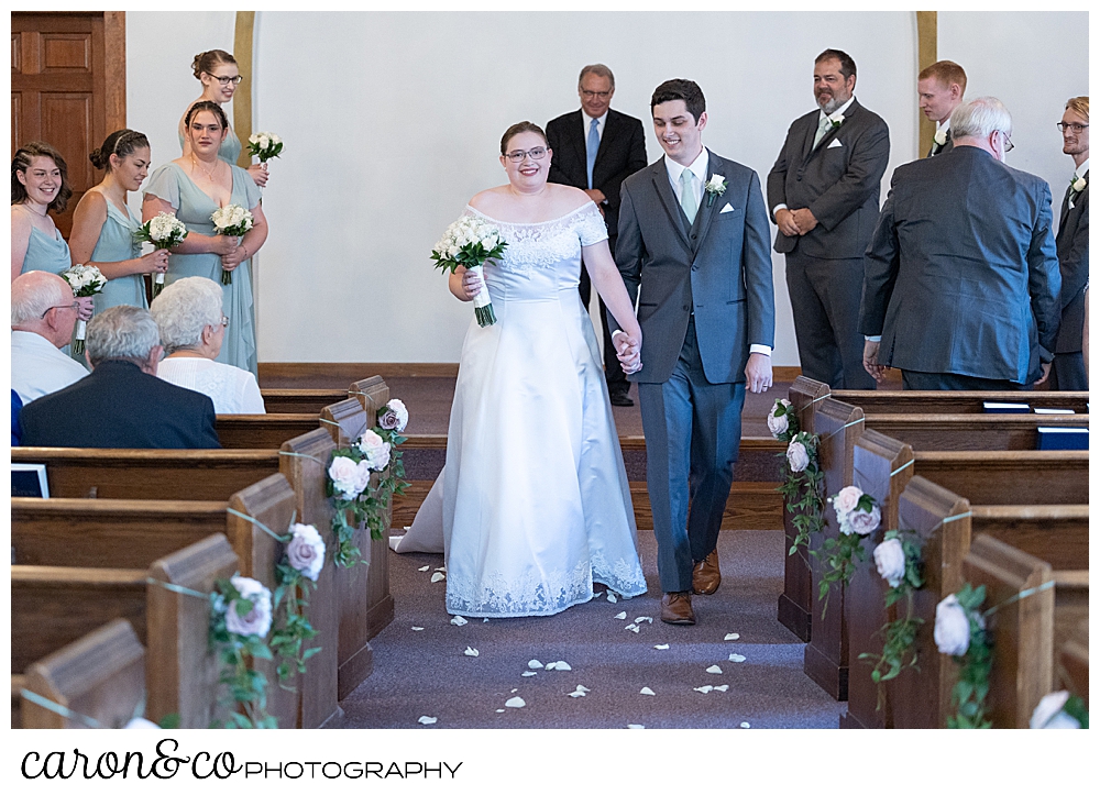 a bride and groom during their recessional at the Peru Maine Baptist Church, during a sweet western Maine wedding ceremony