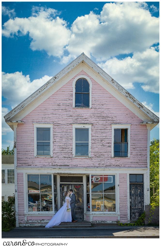 a bride and groom kiss on the steps of a vintage antiques store in Peru Maine