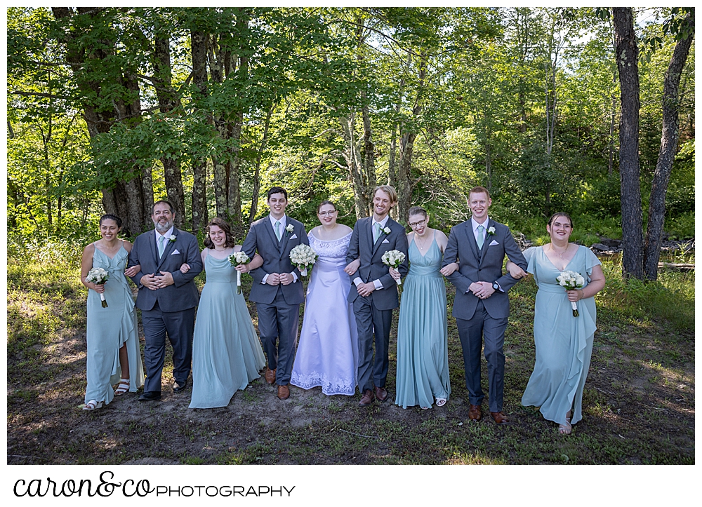 a bridal party with linked arms, walks towards the camera