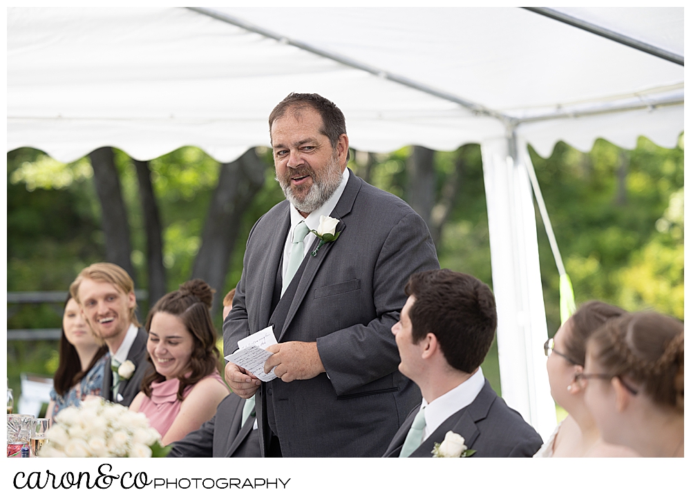 the father of the groom stands to make a toast during a sweet western Maine wedding reception