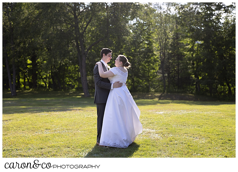 a bride and groom dance in a field during their sweet western Maine wedding reception