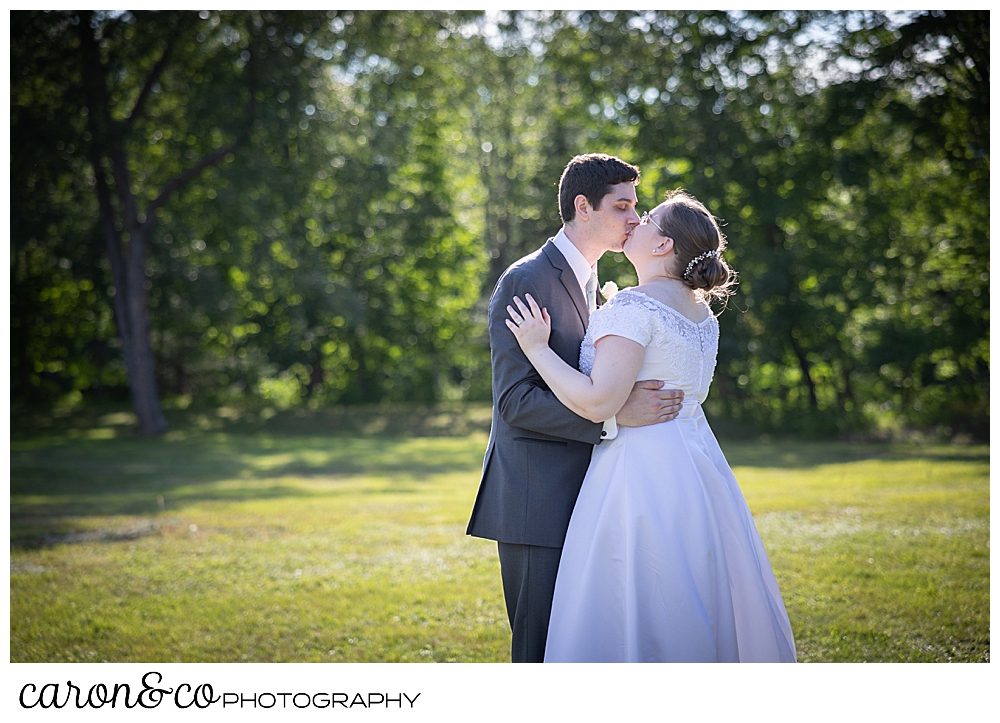 a bride and groom kiss during their first dance in a field during their sweet western Maine wedding reception