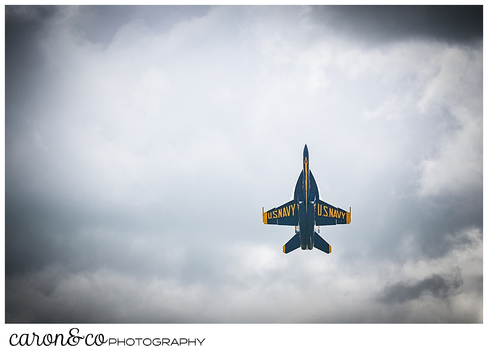 a us navy blue angels airplane, nose up to the sky among the clouds over Brunswick, Maine