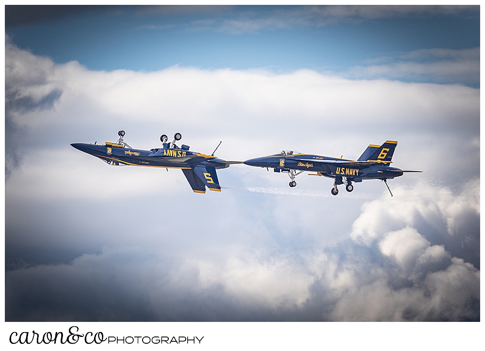 2 us navy blue angels flying in a line, the front plane is upside down