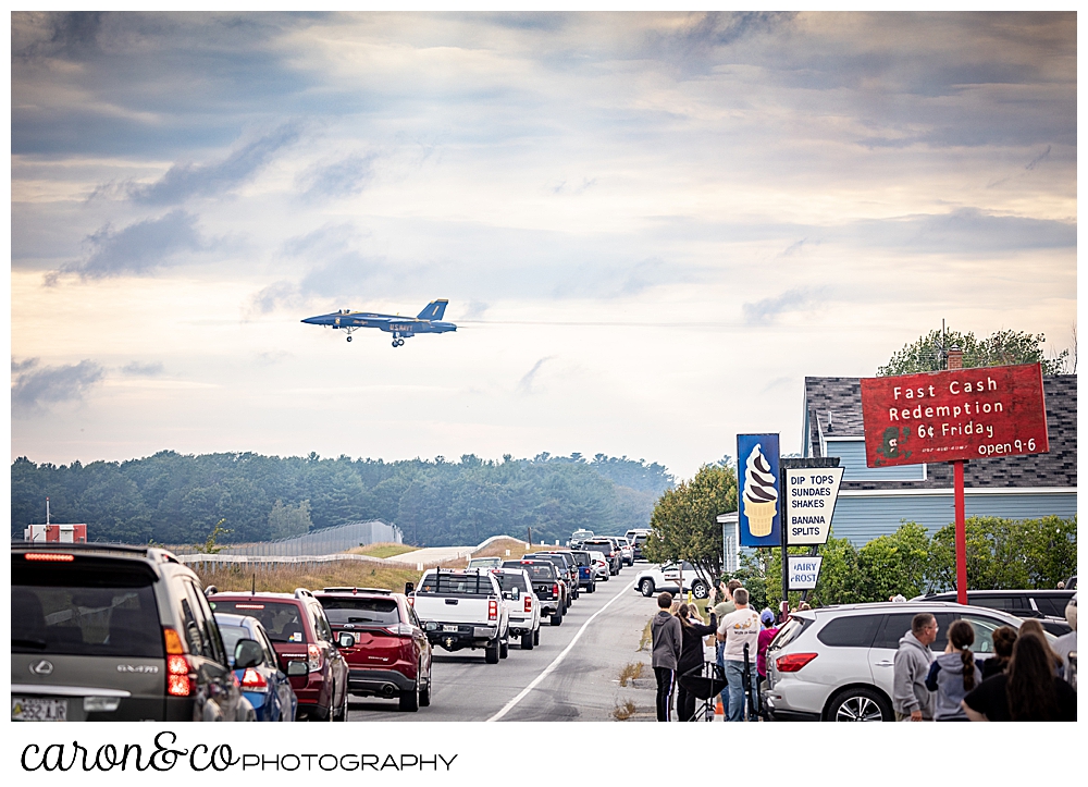 a us navy blue angel flies over Brunswick, Maine, as lines of cars stop to watch