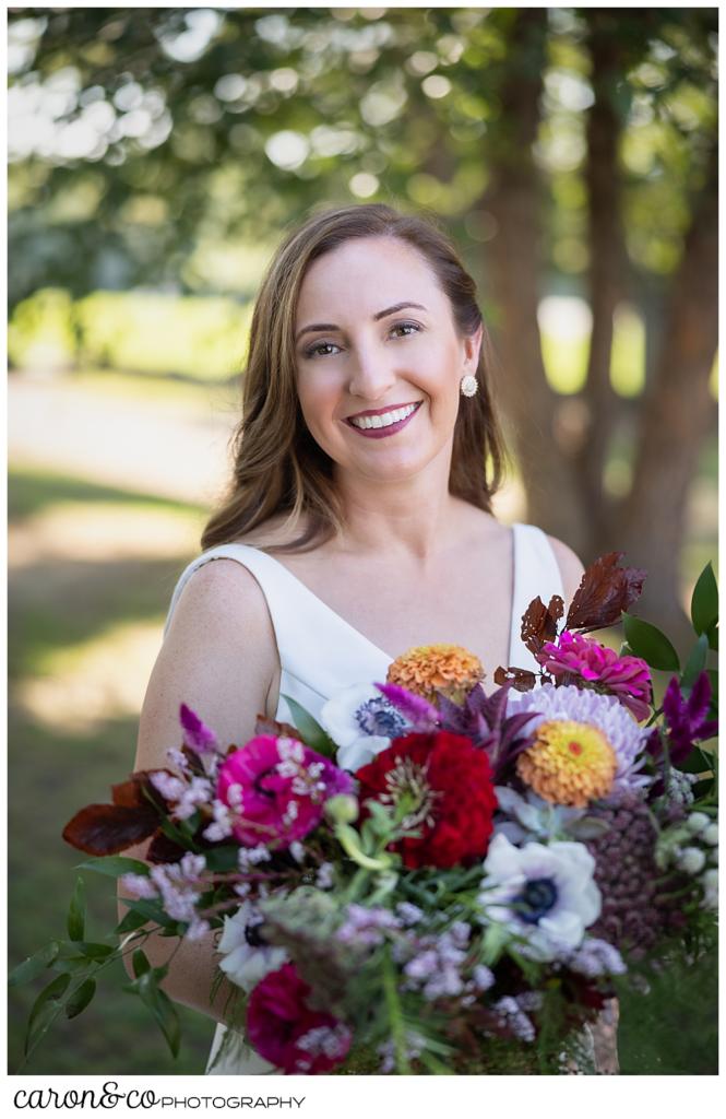 beautiful bridal portrait of a smiling bride, holding a bouquet of brightly colored flowers