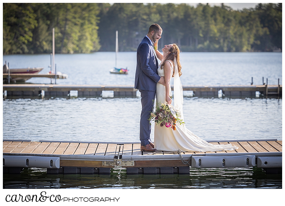 a bride and groom standing face to face on the dock at Camp Skylemar, Trickey Pond, Naples, Maine