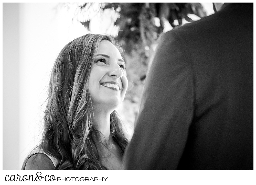 a black and white photo of a bride smiling up at her groom