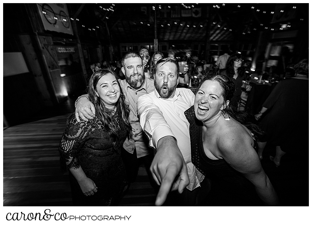 black and white photo of two men and two women dancing, facing the camera, one man is pointing at the photographer