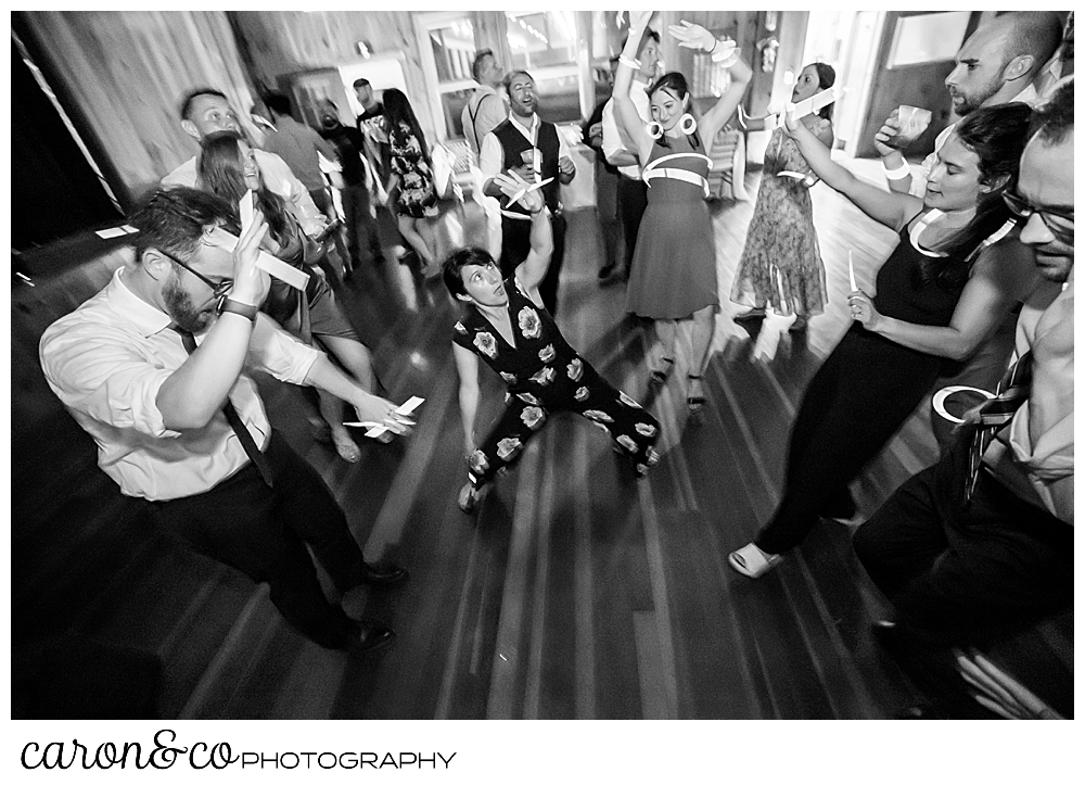 black and white photo of a woman dancing at a camp skylemar wedding reception, there are wedding guests dancing around her