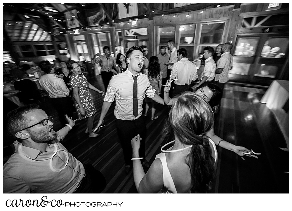 black and white photo of a wedding guest in the middle of the dance floor, singing and dancing