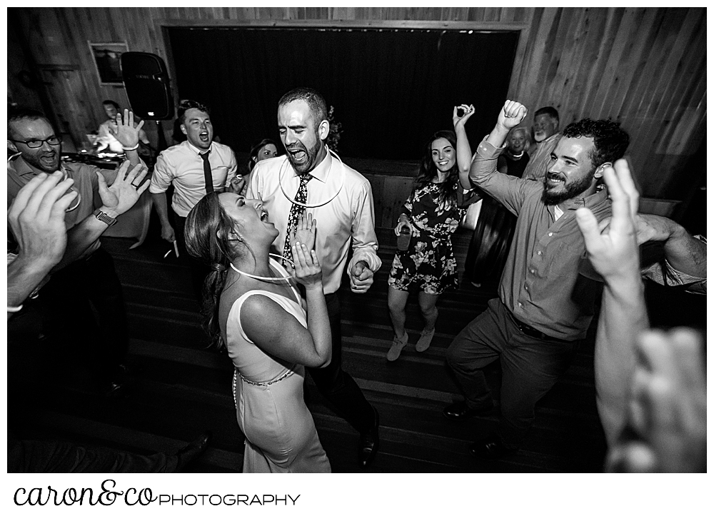 black and white photo of a bride and groom dancing and singing among their guests at their Camp Skylemar wedding reception