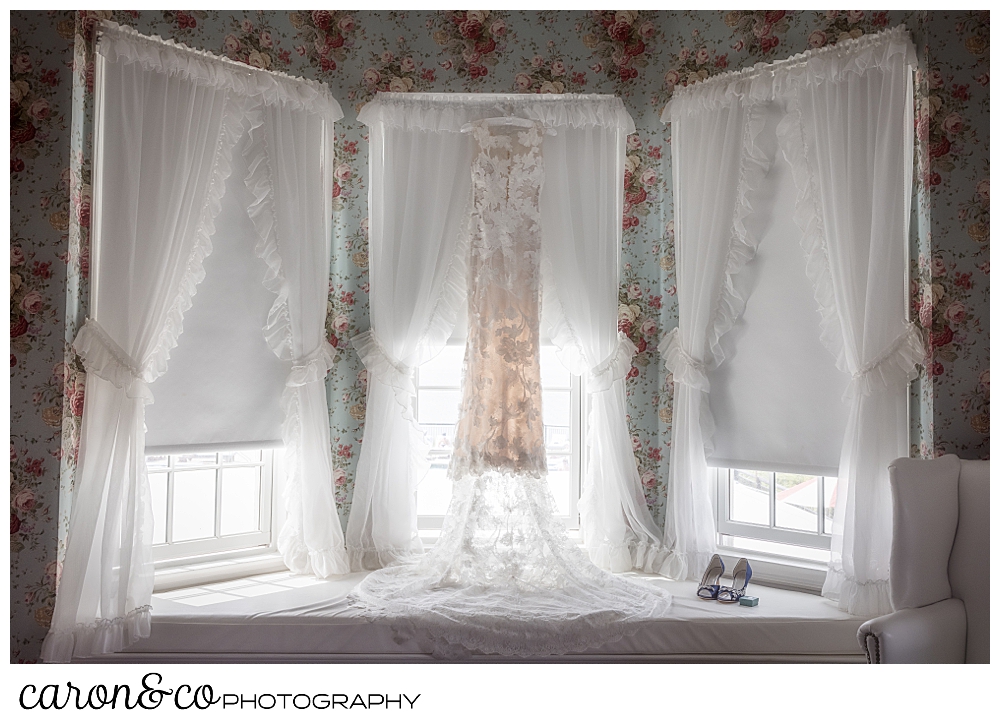 a blush wedding dress hanging in a flowered wallpapered room