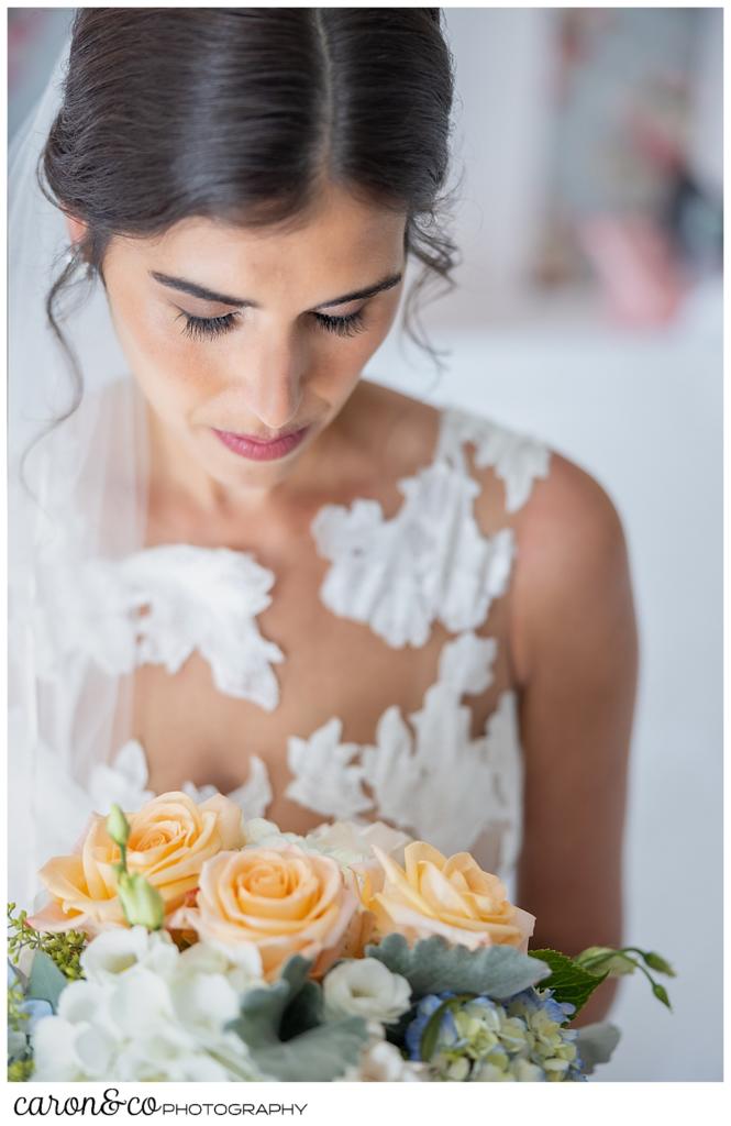 a bridal portrait of a dark haired bride, looking down at her pink, white and green bridal bouquet