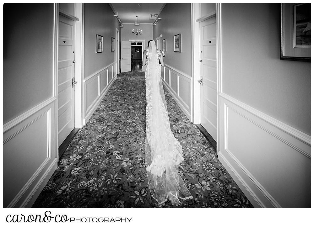 black and white photo of a bride walking down a hallway, away from the camera