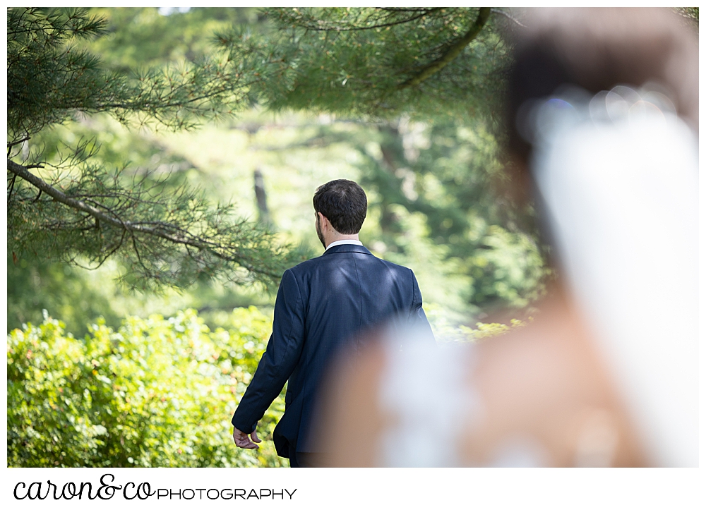 in the foreground is a dark-haired bride wearing a white veil, a groom with his back turned in the background at a Maine wedding day first look at the Colony Hotel Kennebunkport Maine