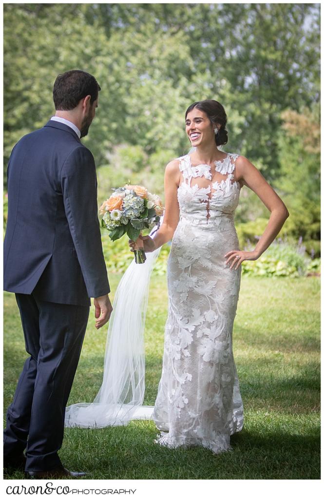 a dark-haired bride, holding a pink, white, blue, and green bouquet, stands before her groom, her hand is on her hip