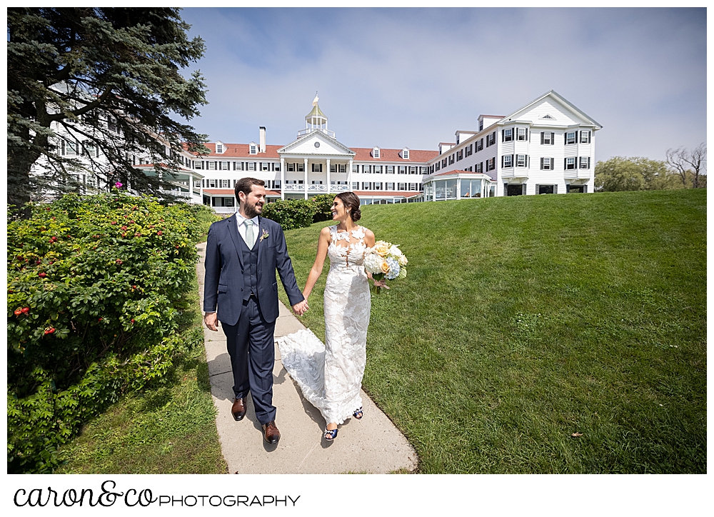 a dark-haired bride and groom walk on the walkway in front of the Colony Hotel, Kennebunkport, Maine