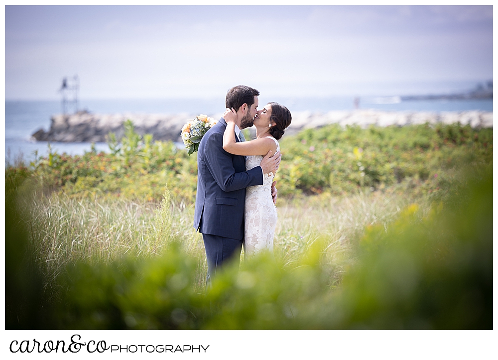 a dark-haired bride and groom kiss in the dunes at Colony Beach, Kennebunkport, Maine