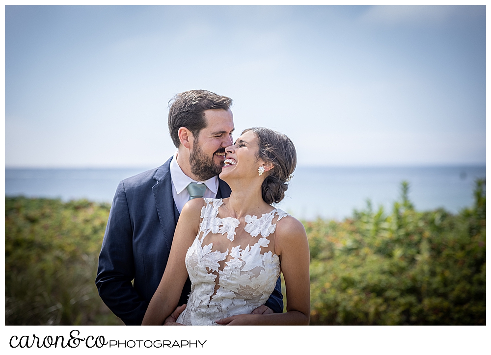 a dark-haired bride and groom smile as they embrace