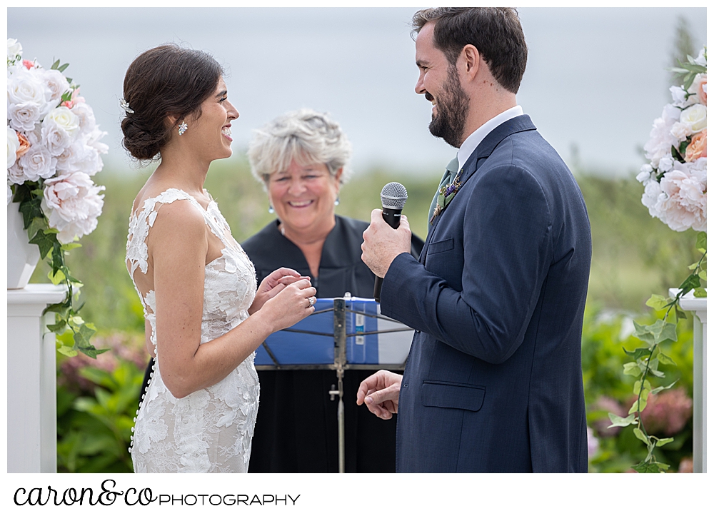 a bride and groom stand before their officiant, the groom has a microphone and is speaking his vows