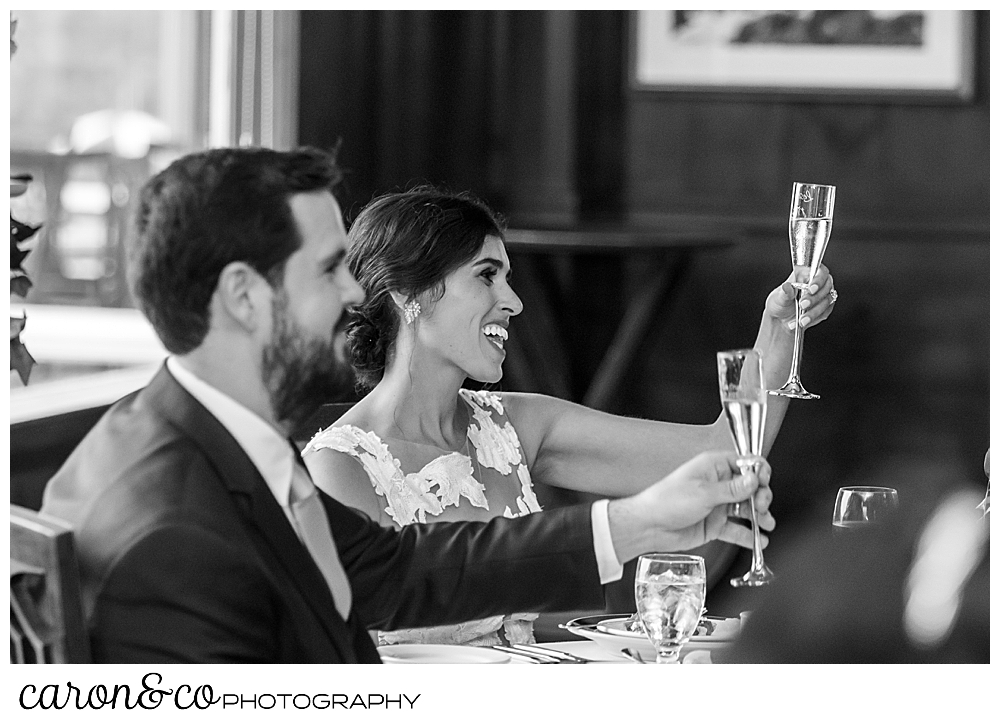 black and white photo of a bride and groom lifting their champagne glasses for a toast