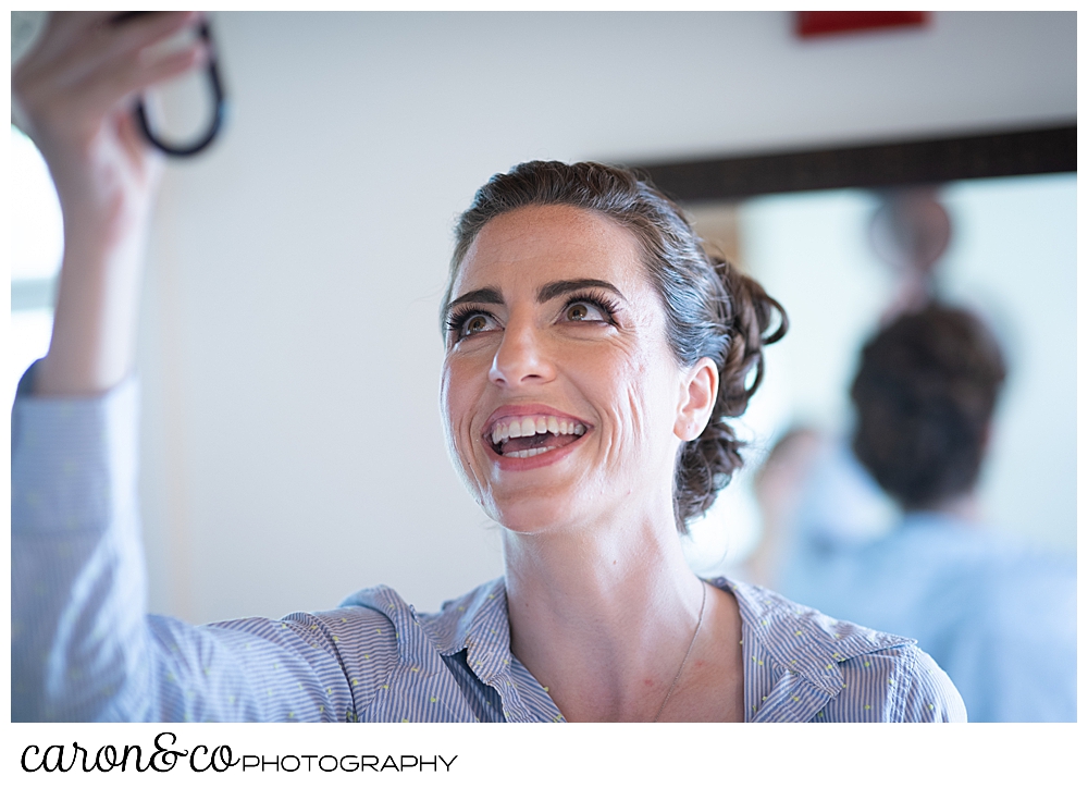 a bride checks her hair in a mirror behind her, and smiles